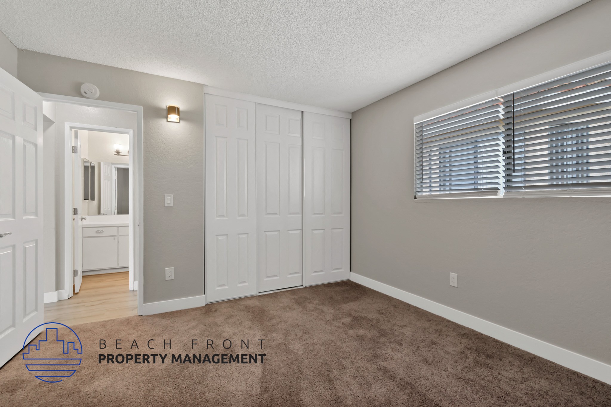 A room with a carpeted floor and a logo for Beach Front Property Management.